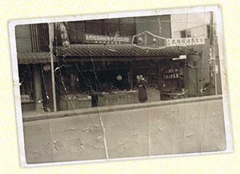 1956年北野せともの店の前で祖母におんぶされている写真です。